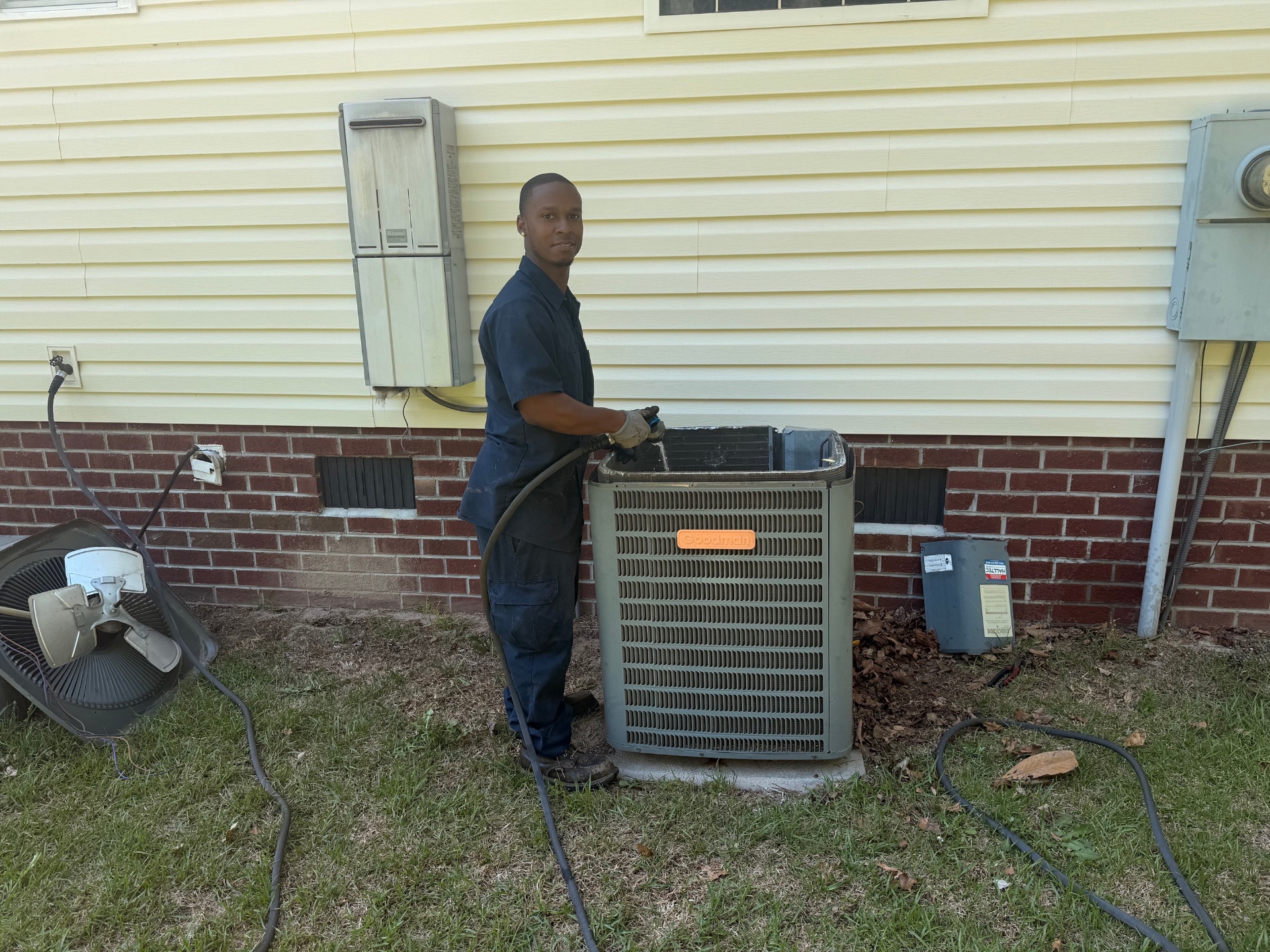 Barrett HVAC technician servicing an outdoor AC condenser unit