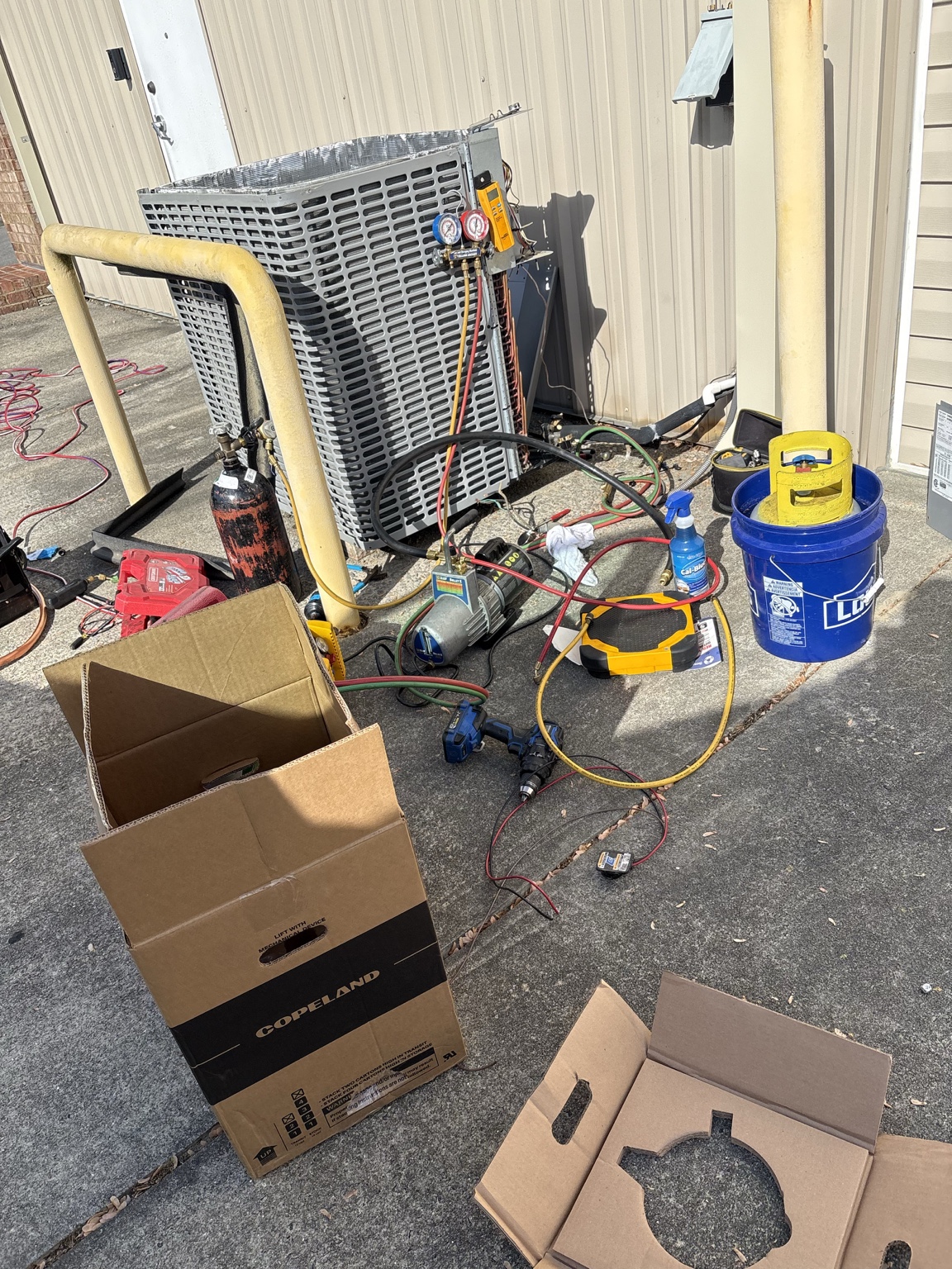 Commercial HVAC condenser repair in progress with manifold gauges and tools